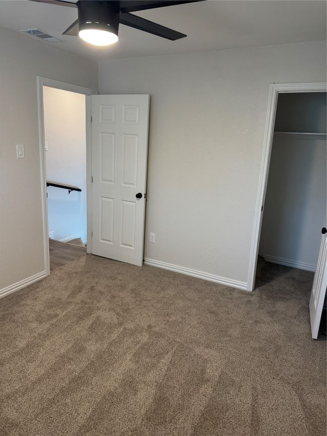 Unfurnished bedroom with carpet, a walk in closet, a closet, baseboards, and ceiling fan | Image 12