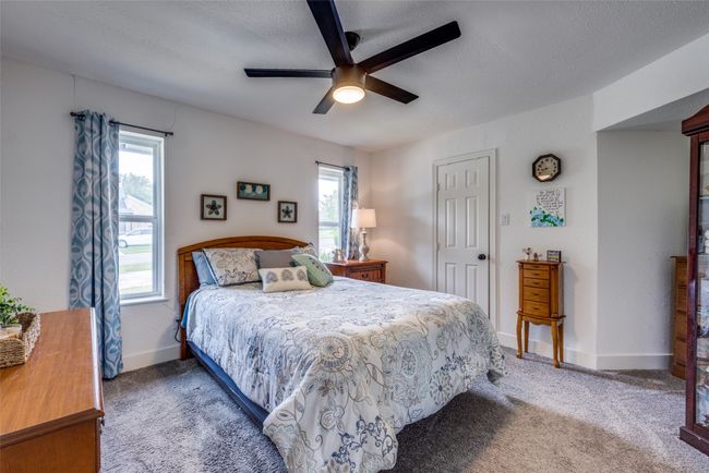 Bedroom with carpet flooring, multiple windows, a textured ceiling, a ceiling fan, and baseboards | Image 14