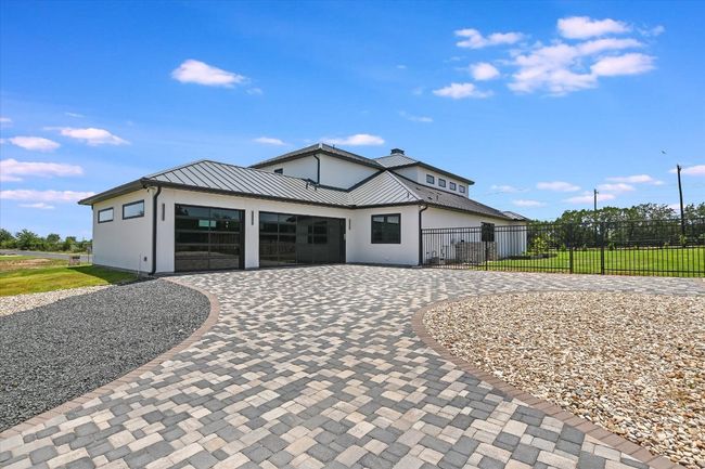 Modern farmhouse with curved paver driveway, a standing seam metal roof | Image 5