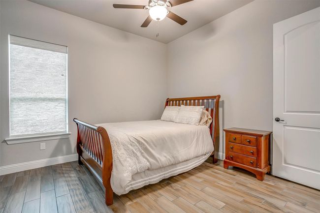 Bedroom with wood finished floors, multiple windows, ceiling fan, and lofted ceiling | Image 27