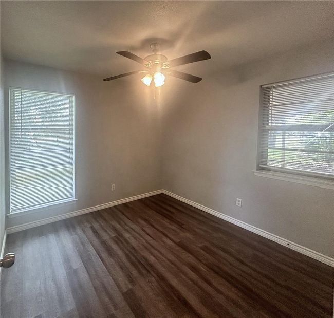 Empty room with ceiling fan, dark wood-style floors, and baseboards | Image 15