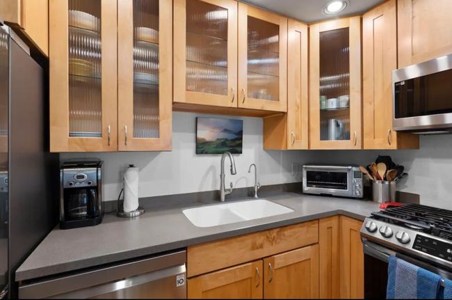 Kitchen with appliances with stainless steel finishes, glass insert cabinets, light brown cabinetry, and recessed lighting | Image 8