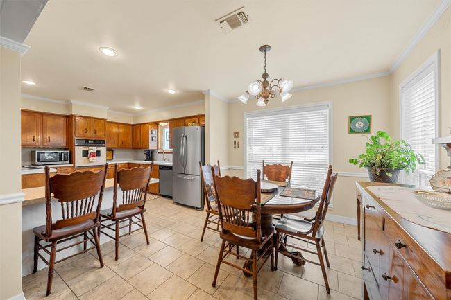 Dining area with a chandelier, ornamental molding, light tile patterned flooring, and recessed lighting | Image 7