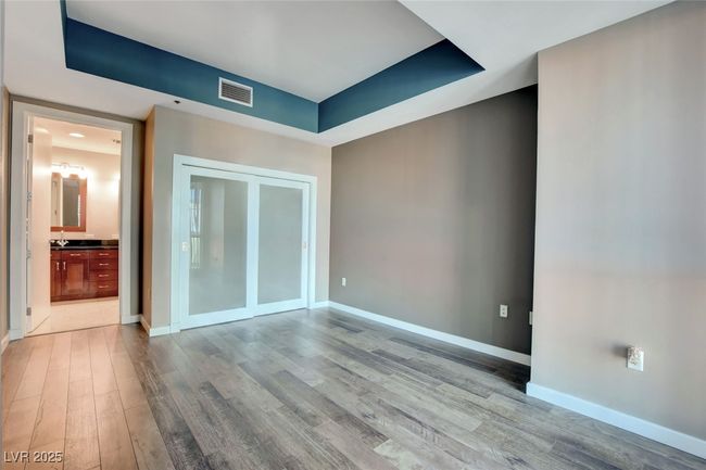 Primary bedroom featuring connected bathroom, baseboards, wood finished floors, and visible vents | Image 18