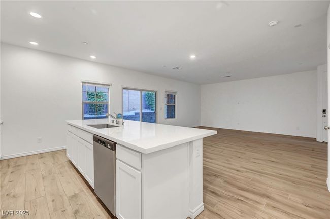Kitchen featuring white cabinetry, a sink, dishwasher, light wood finished floors, and an island with sink | Image 14