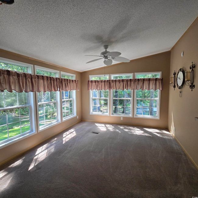 Empty room with lofted ceiling, a ceiling fan, a textured ceiling, and carpet | Image 20