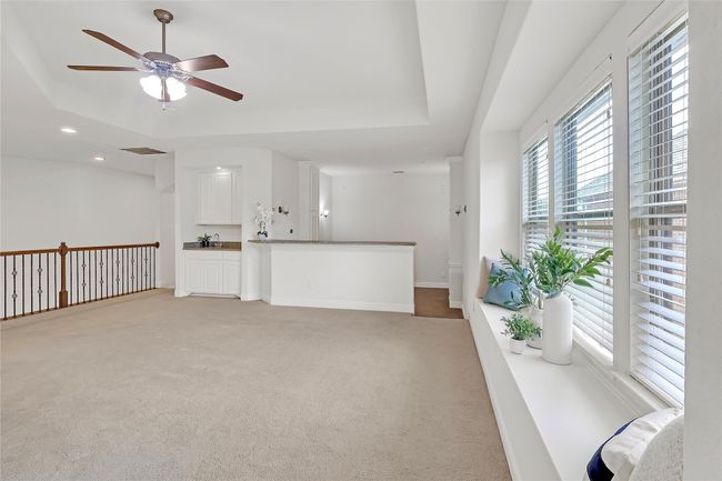 Unfurnished living room with light colored carpet, ceiling fan, a raised ceiling, and recessed lighting | Image 24