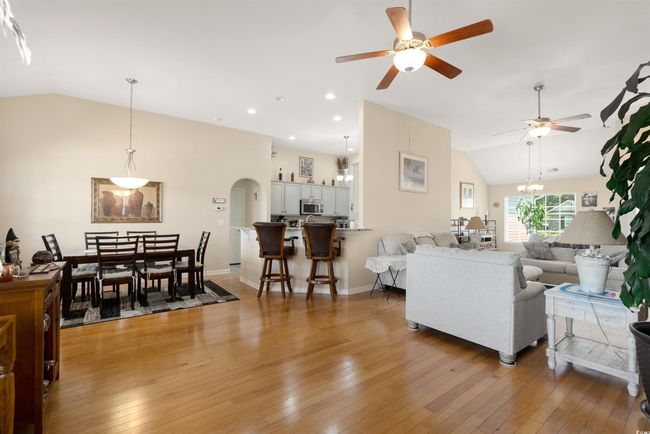 Living room with vaulted ceiling, ceiling fan, light wood finished floors, arched walkways, and baseboards | Image 12