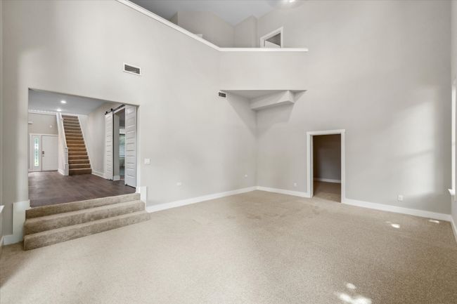 Unfurnished living room with a high ceiling, stairway, carpet, and baseboards | Image 17