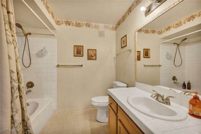 Bathroom with toilet, baseboards, visible vents, shower / tub combo, and vanity | Image 28
