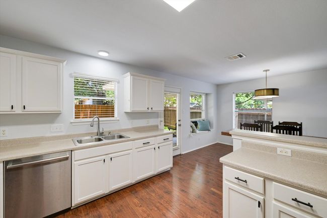 Kitchen with dishwasher, dark wood-style floors, pendant lighting, white cabinets, and light countertops | Image 7
