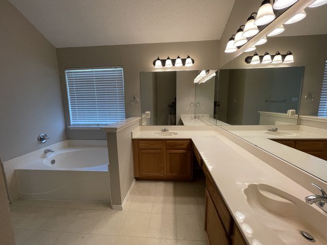 Bathroom with double vanity, a bath, tile patterned flooring, and a textured ceiling | Image 7