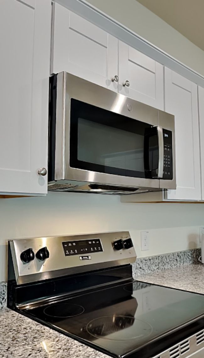Kitchen view of stainless steel appliances, white cabinetry, and light stone counters | Image 13