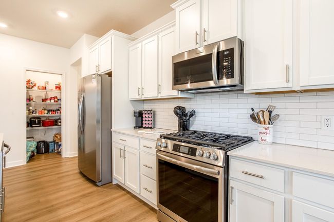Showcasing a modern gas range, built-in microwave, and a walk-in pantry for maximum storage convenience. | Image 10