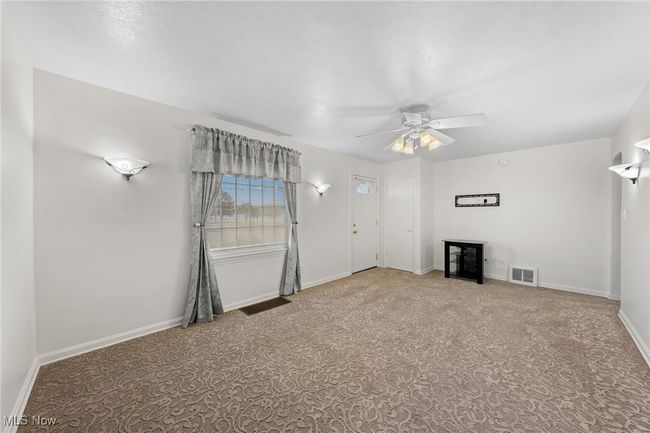 Unfurnished living room with ceiling fan and carpet floors | Image 7