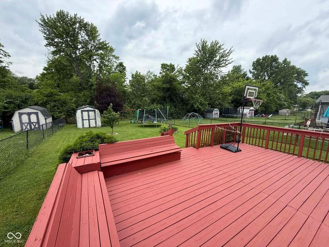wooden deck featuring a shed, a trampoline, and a fenced backyard | Image 9