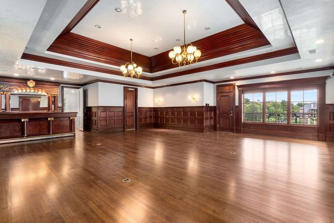 Great room has a raised ceiling, chandelier, ornamental molding, decorative wall, wood floors and outdoor balcony overlooking the 12th Fairway Green | Image 31