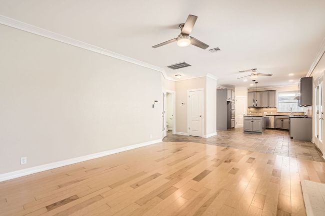 Unfurnished living room featuring light wood-style flooring, a ceiling fan, and crown molding | Image 12