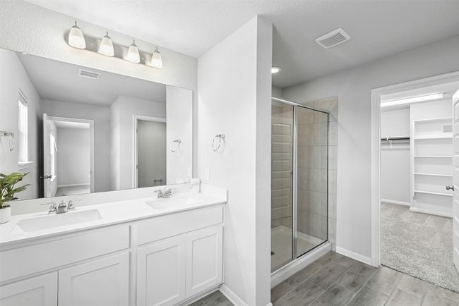 Full bath with a stall shower, a walk in closet, double vanity, and wood finish floors | Image 27