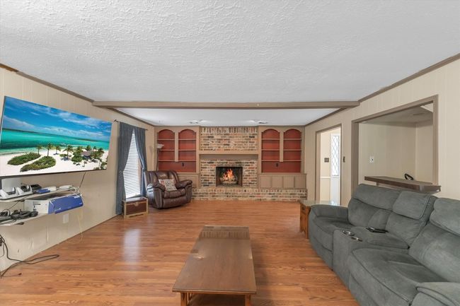 Living area featuring wood finished floors, a fireplace, built in features, and beamed ceiling | Image 18
