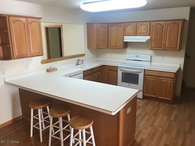 Kitchen with white appliances, dark hardwood / wood-style floors, kitchen peninsula, and sink | Image 3