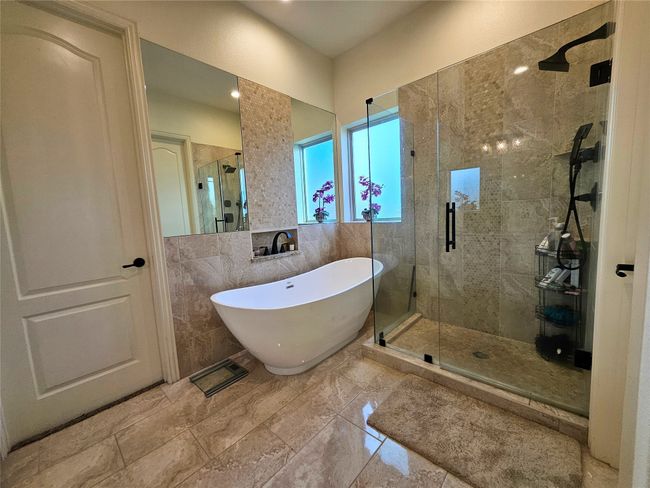 Bathroom with a stall shower, a soaking tub, and tile walls | Image 25