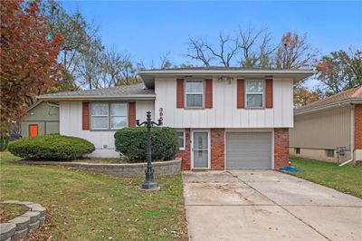 Split level home featuring a front lawn and a garage | Image 1