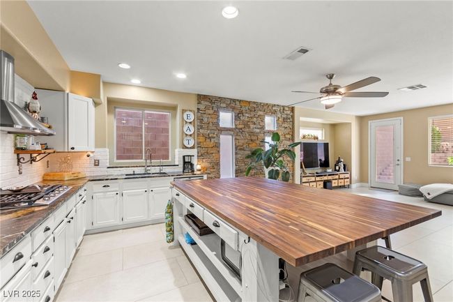Kitchen featuring stainless steel gas cooktop, butcher block countertops, a sink, open shelves, and backsplash | Image 13