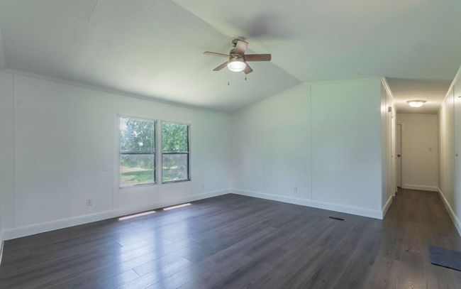 Empty room featuring ceiling fan, dark wood finished floors, and vaulted ceiling | Image 6