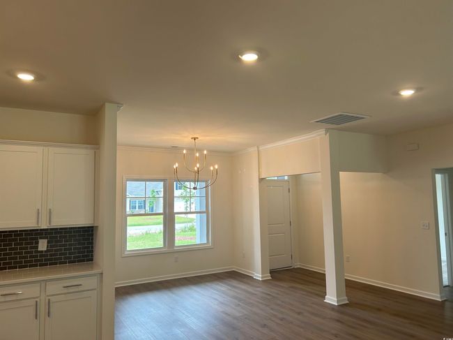 Unfurnished dining area with a chandelier, baseboards, dark wood-type flooring, crown molding, and recessed lighting | Image 17