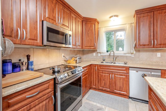 Kitchen featuring appliances with stainless steel finishes, backsplash, and brown cabinets | Image 9