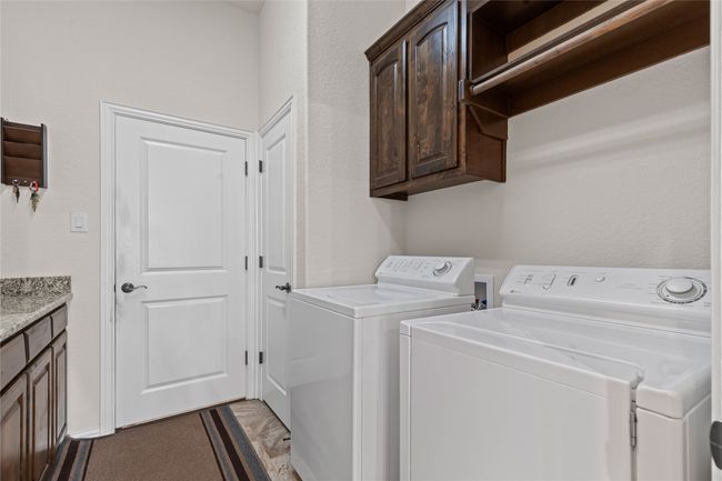 Laundry area with cabinet space, separate washer and dryer, and a textured wall | Image 13