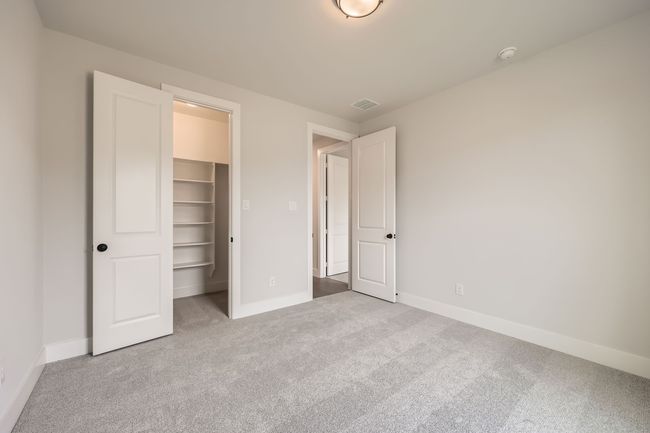 Unfurnished bedroom with a walk in closet, carpet, baseboards, visible vents, and a closet | Image 24