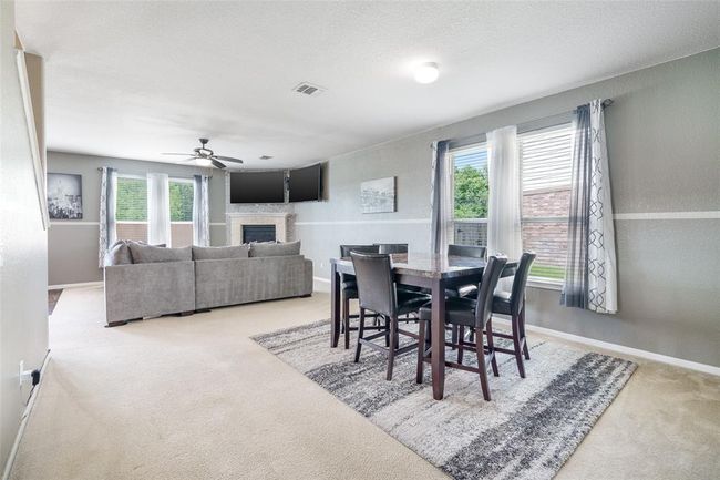 The dining area, perfectly situated between the living room and home office, features cozy carpet flooring, soft dome lighting, and windows with privacy blinds that brings in just the right amount of natural light. | Image 5