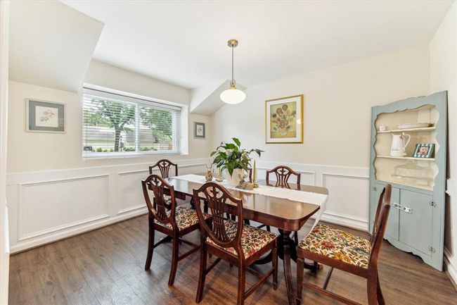 Elegant dining room with luxury vinyl flooring, pendant lighting, and classic wainscoting. | Image 4