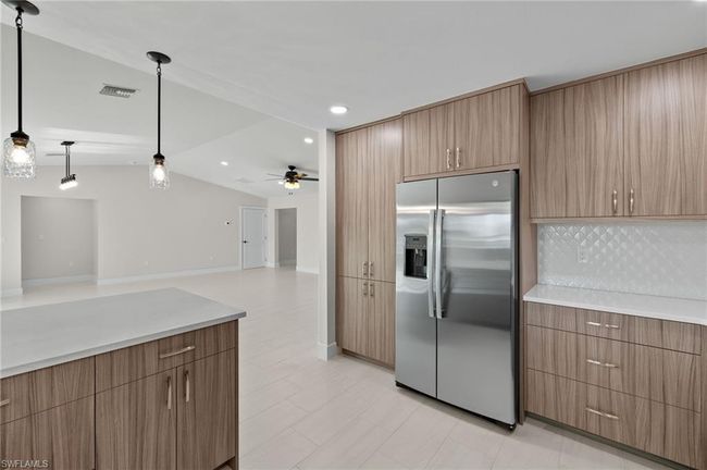 Kitchen with light tile patterned flooring, ceiling fan, high end refrigerator, decorative backsplash, and decorative light fixtures | Image 9