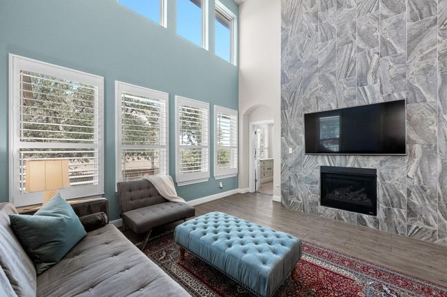 Living room with wood finished floors, a large fireplace, a towering ceiling, and arched walkways | Image 6