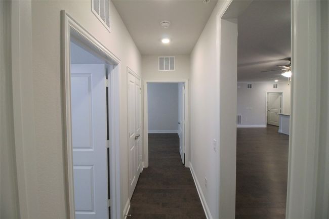 Corridor with dark wood-style floors, visible vents, and baseboards | Image 7