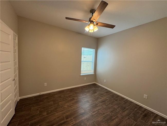 Spare room featuring dark wood-style flooring, ceiling fan, and baseboards | Image 14