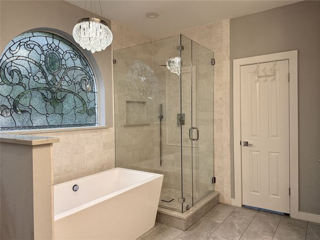 Bathroom featuring a notable chandelier, plenty of natural light, a soaking tub, and a stall shower | Image 22