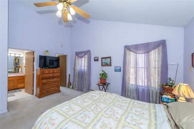 Carpeted bedroom with ensuite bathroom, high vaulted ceiling, and a ceiling fan | Image 25