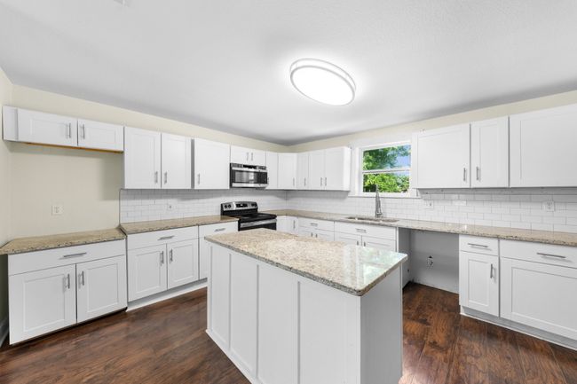 Kitchen featuring appliances with stainless steel finishes, a sink, tasteful backsplash, and white cabinetry | Image 12