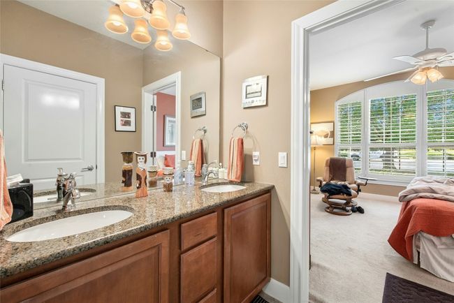 Full bath with double vanity, a ceiling fan, and a chandelier | Image 15