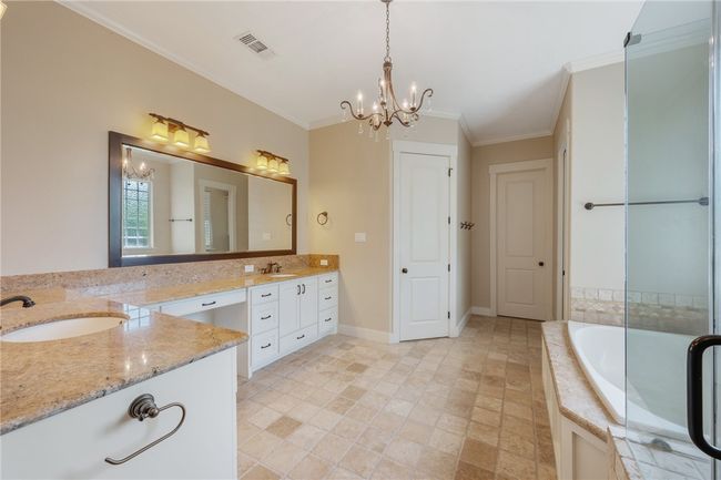 Bathroom with a chandelier, vanity, tiled tub, and crown molding | Image 24