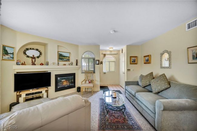 Living room with a glass covered fireplace and visible vents | Image 21