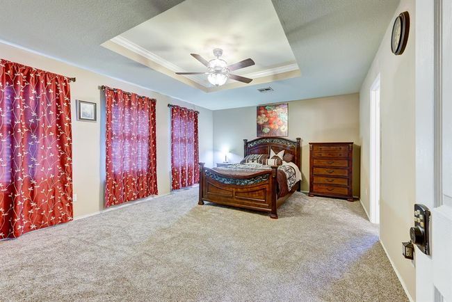 Carpeted bedroom with a tray ceiling, ornamental molding, and ceiling fan | Image 12
