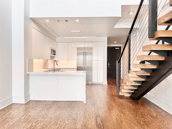 Kitchen featuring appliances with stainless steel finishes, modern cabinets, light wood-style floors, white cabinets, and light countertops | Image 5