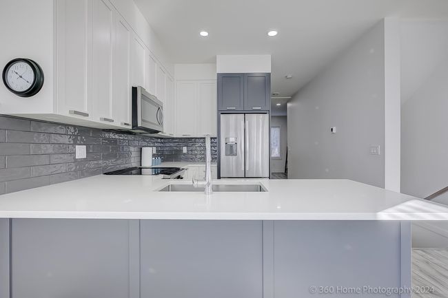 Kitchen with stainless steel appliances, a peninsula, tasteful backsplash, light countertops, and white cabinets | Image 26
