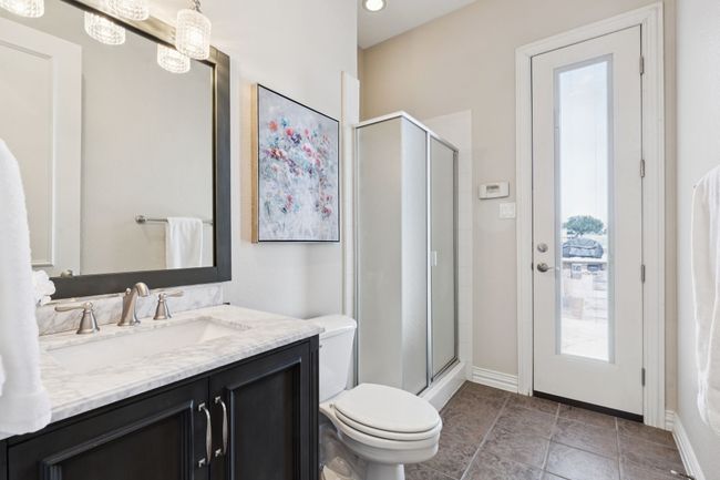 This full bath is near the game room and kitchen and is available for guests. This bath with tile flooring can be accessed directly from the pool area. Leave the pool and hit the shower without tracking wet footprints in the house. The bath has standing shower, oversized tile, framed mirror and wave sink with brushed nickel fixtures. | Image 27