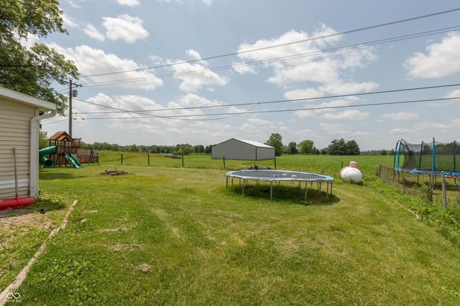 view of grassy yard featuring a trampoline, a playground, a view of countryside, and an outbuilding | Image 21